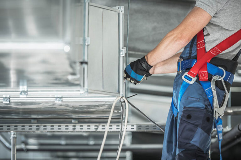 A technician working on a heating and cooling air shaft building (HVAC)